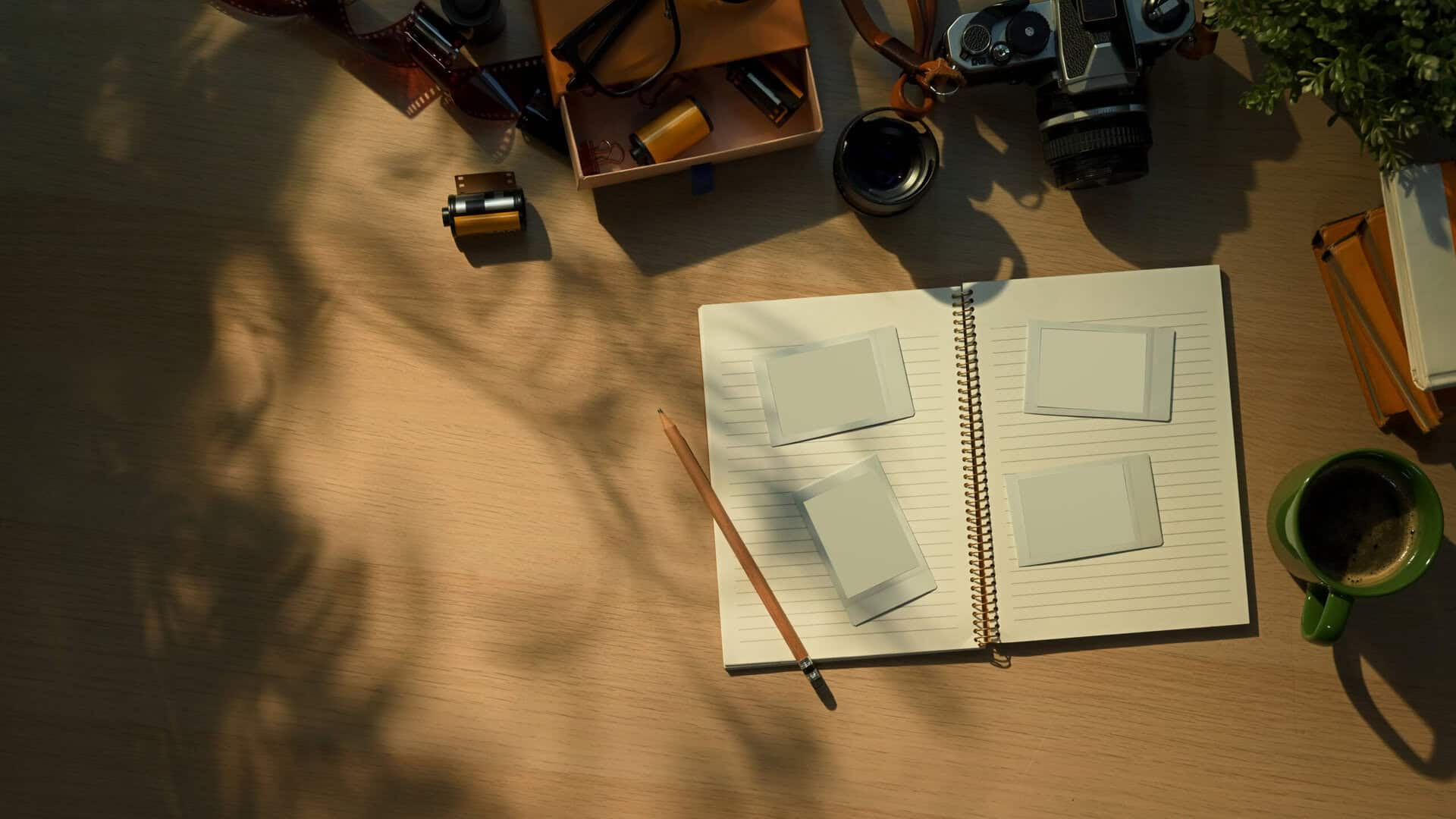 Creative workspace with vintage camera, notebook, and coffee cup in warm morning sunlight
