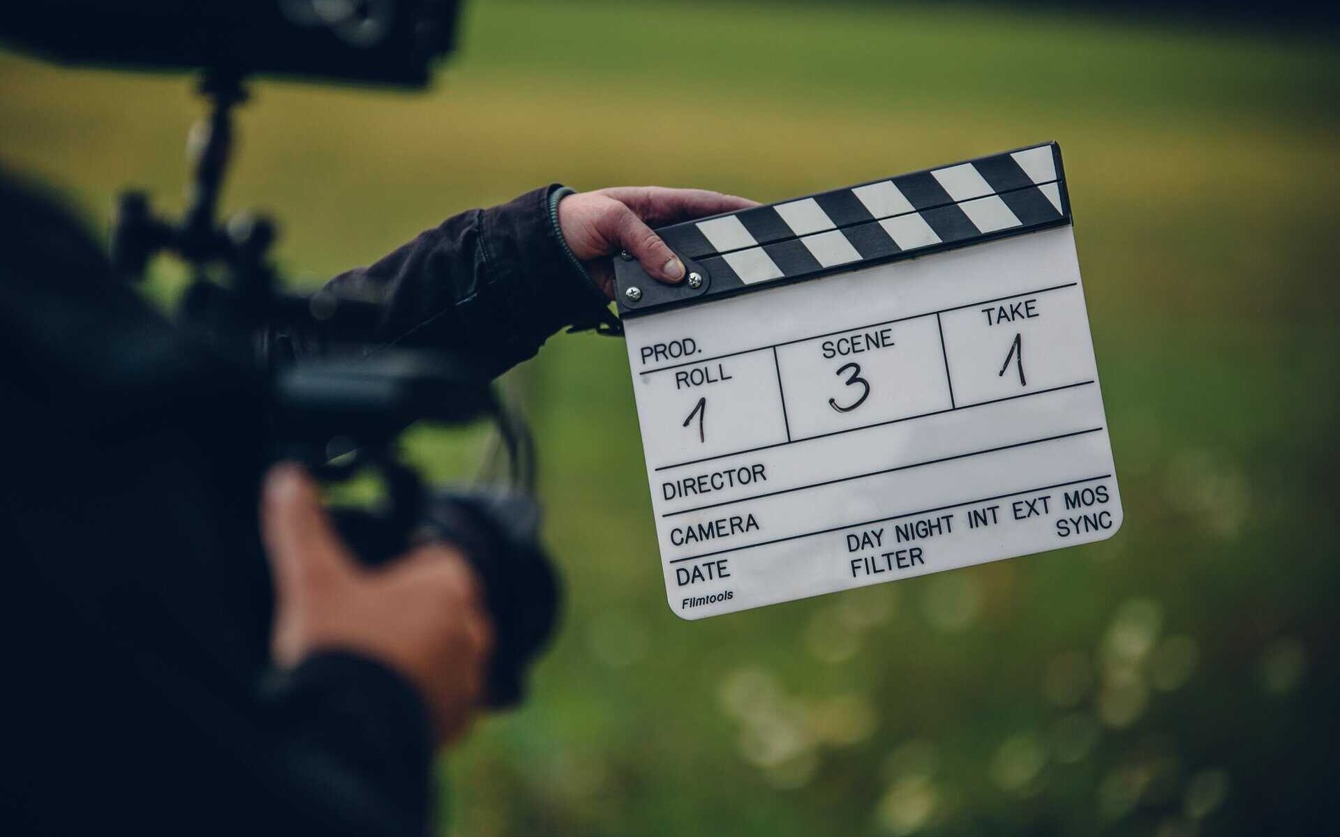 A shallow focus shot of the cameraman holding a clapperboard in the field