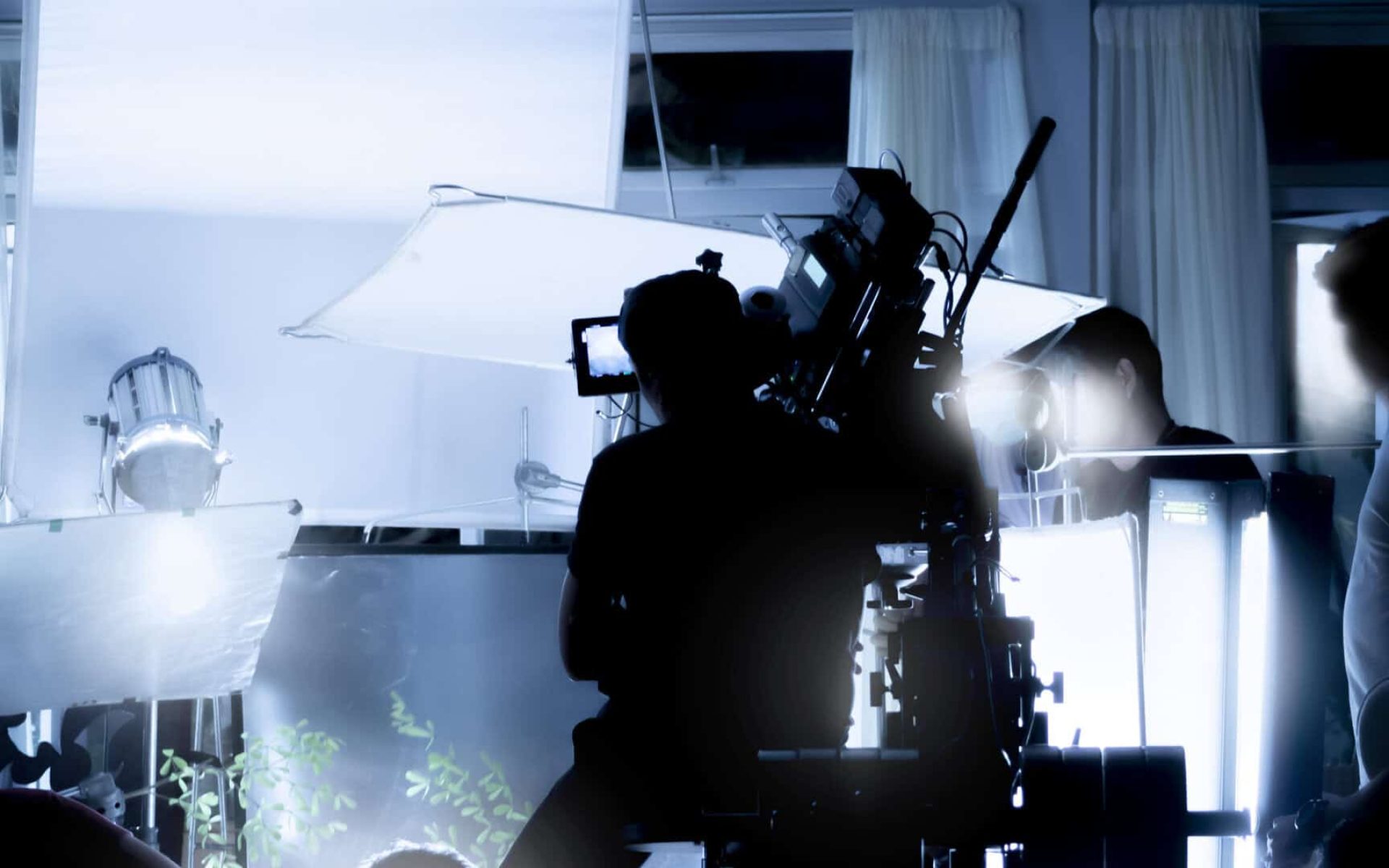 Silhouette images of video production behind the scenes or b-roll or making of TV commercial movies that film crew team lightman and videos cameraman working together with movie director in studio.
